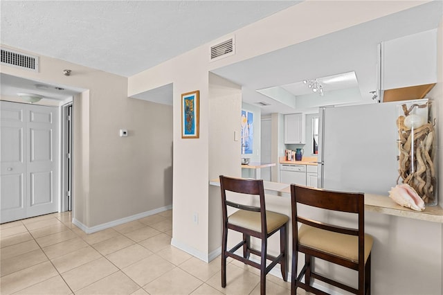 kitchen featuring light tile patterned floors, light countertops, visible vents, and white cabinets