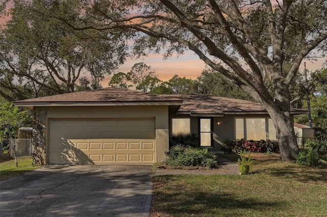 ranch-style house with a garage and a lawn