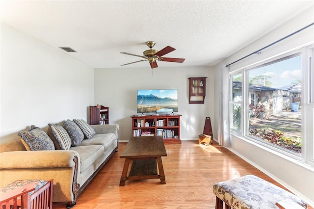 living room featuring ceiling fan, wood-type flooring, and a textured ceiling