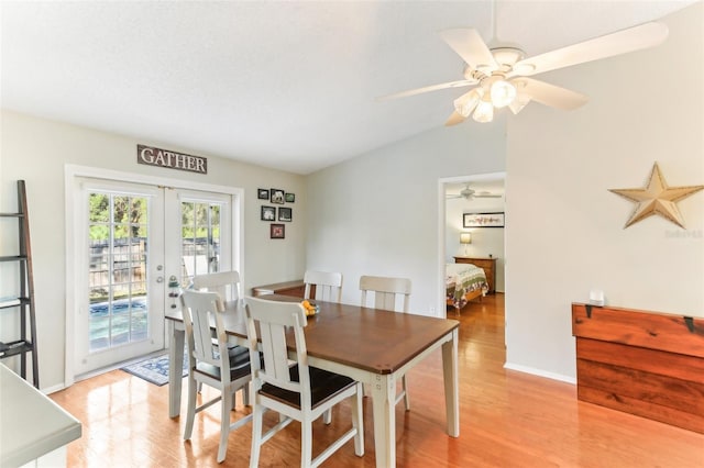 dining area with vaulted ceiling, ceiling fan, light wood-type flooring, and french doors