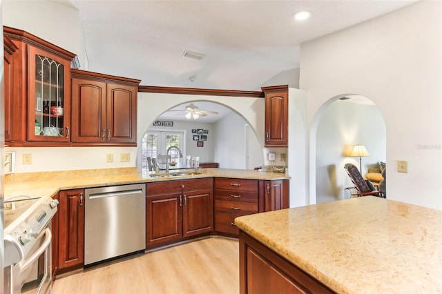 kitchen with vaulted ceiling, appliances with stainless steel finishes, sink, light hardwood / wood-style floors, and light stone countertops