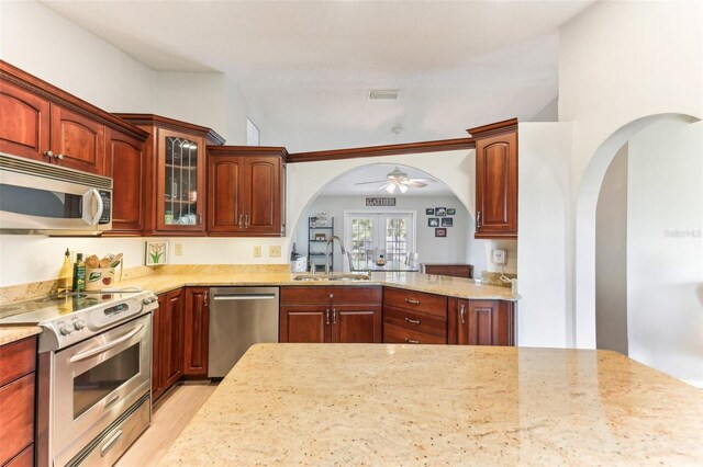 kitchen featuring sink, light hardwood / wood-style flooring, appliances with stainless steel finishes, light stone counters, and french doors