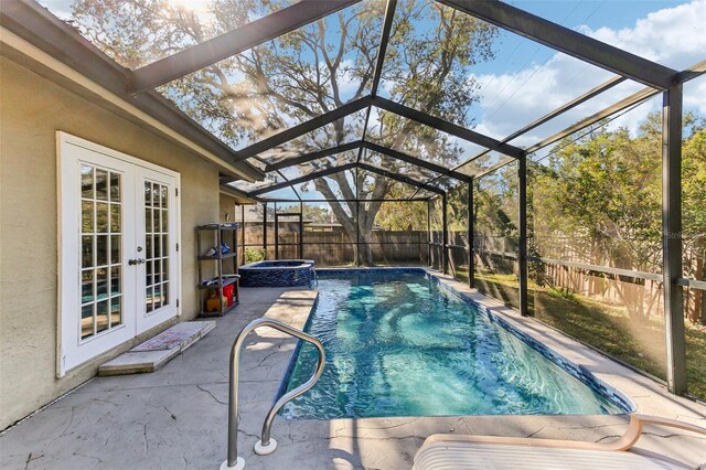 view of swimming pool featuring a patio, a lanai, french doors, and an in ground hot tub