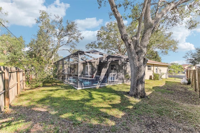 rear view of house featuring a fenced in pool, a lanai, and a lawn