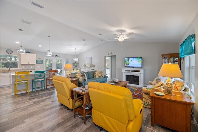 living room with vaulted ceiling, ceiling fan, light wood-type flooring, and french doors