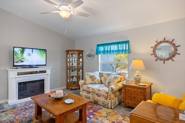 living room with ceiling fan, lofted ceiling, a fireplace, and light hardwood / wood-style flooring