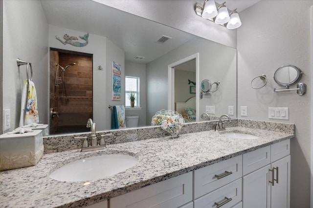 bathroom with tiled shower, vanity, and toilet