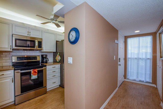 kitchen with backsplash, light hardwood / wood-style floors, a textured ceiling, and appliances with stainless steel finishes