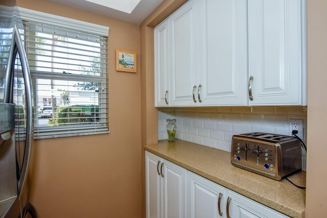 kitchen with tasteful backsplash and white cabinets