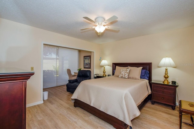 bedroom with ceiling fan, light hardwood / wood-style flooring, and a textured ceiling