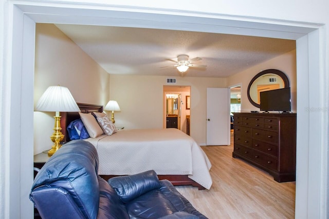 bedroom featuring connected bathroom and light hardwood / wood-style flooring