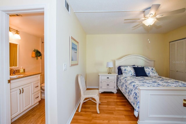 bedroom with ceiling fan, sink, light wood-type flooring, and a closet