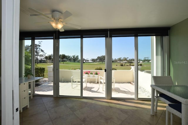 doorway to outside featuring expansive windows, ceiling fan, and a wealth of natural light