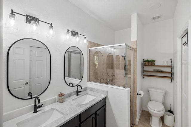 bathroom featuring vanity, toilet, and a shower with shower door