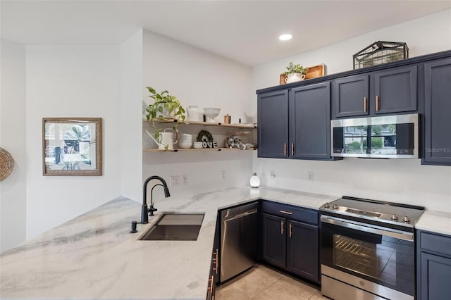 kitchen with blue cabinets, sink, light tile patterned floors, stainless steel appliances, and light stone countertops