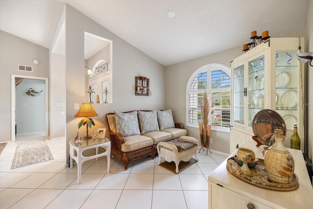 living area with light tile patterned flooring, lofted ceiling, and a textured ceiling