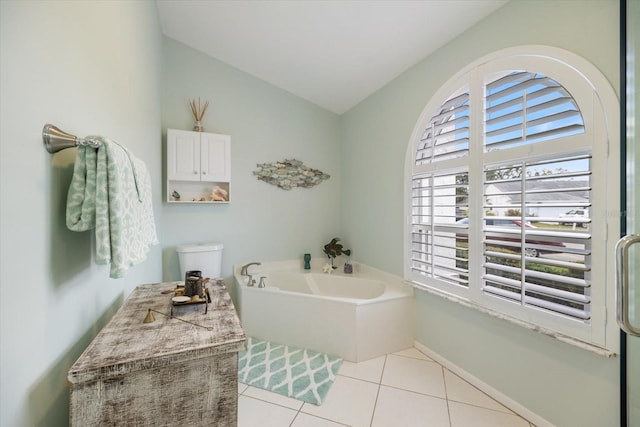 bathroom featuring tile patterned floors, toilet, vaulted ceiling, and a washtub