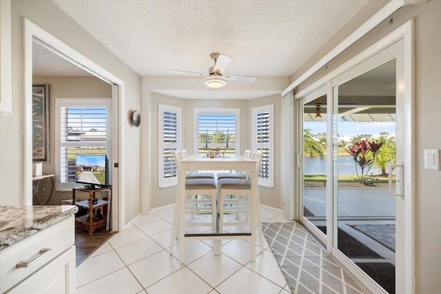 interior space featuring ceiling fan, a textured ceiling, and light tile patterned floors