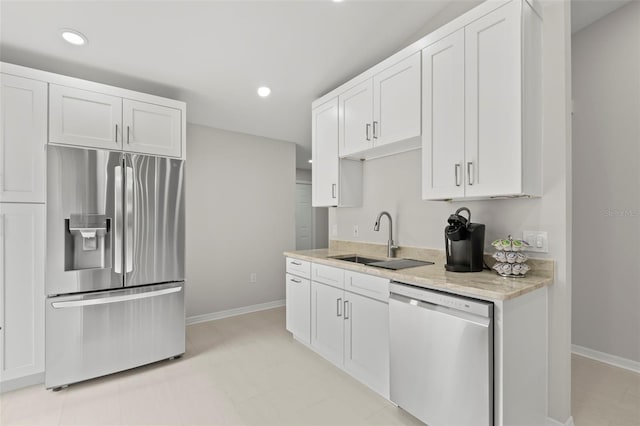 kitchen with appliances with stainless steel finishes, sink, white cabinets, and light stone counters