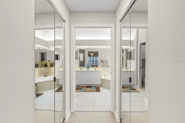 bathroom with tile patterned flooring, vanity, a bath, and toilet