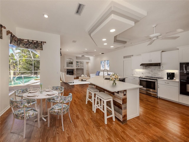 1093 Laurel Woods Dr, Nokomis, FL 34275 - kitchen with stainless steel range with electric cooktop, under cabinet range hood, ceiling fan, wood finished floors, and recessed lighting