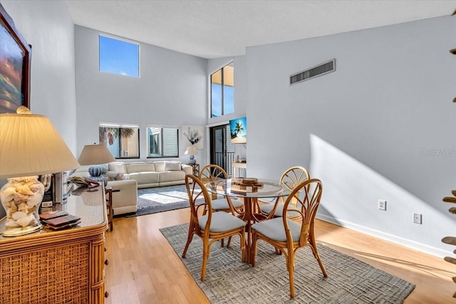 dining area with a towering ceiling and light hardwood / wood-style flooring