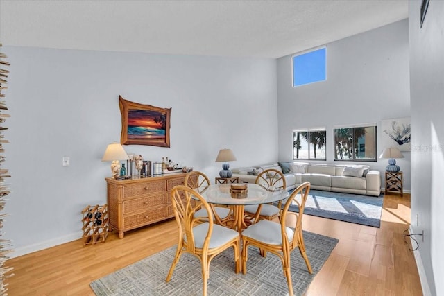 dining space with a towering ceiling and hardwood / wood-style floors