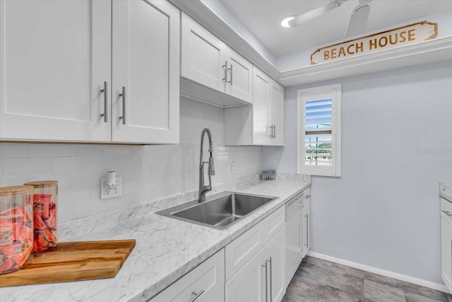 kitchen featuring sink, white cabinets, backsplash, ceiling fan, and light stone counters