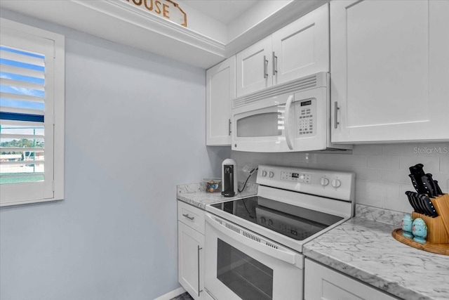 kitchen with backsplash, white appliances, light stone countertops, and white cabinets