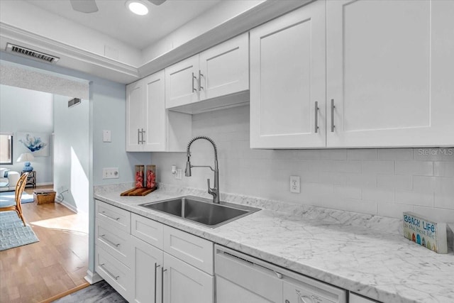 kitchen with sink, white cabinetry, light hardwood / wood-style flooring, light stone countertops, and decorative backsplash