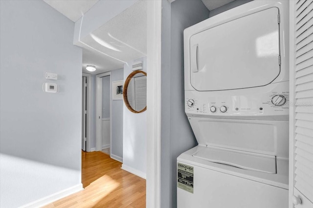 laundry room featuring stacked washer / drying machine and hardwood / wood-style floors