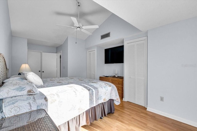 bedroom featuring lofted ceiling, hardwood / wood-style floors, multiple closets, and ceiling fan