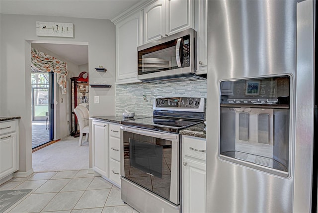 kitchen featuring stainless steel appliances, white cabinets, light tile patterned flooring, decorative backsplash, and dark stone counters