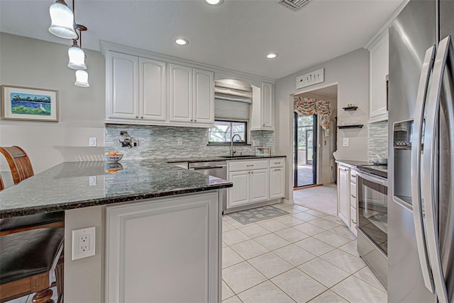 kitchen featuring decorative light fixtures, kitchen peninsula, white cabinets, and appliances with stainless steel finishes