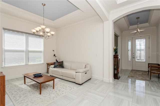 living room featuring crown molding, a notable chandelier, and a tray ceiling