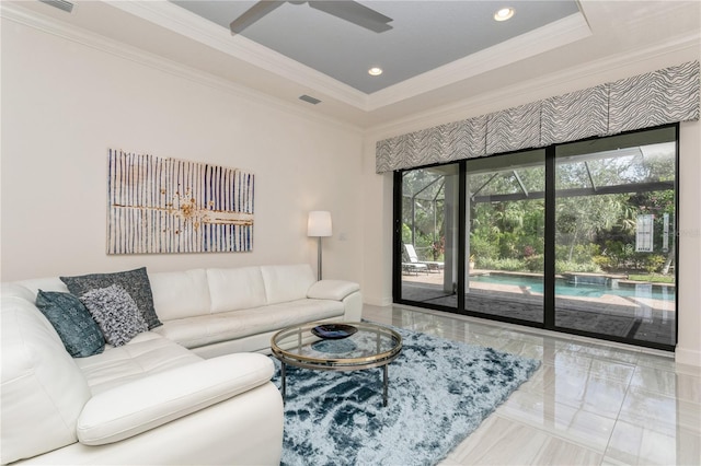 living room with a tray ceiling, ornamental molding, and ceiling fan