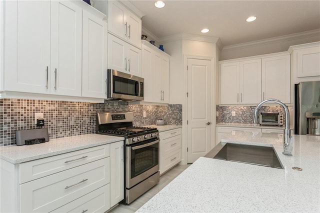 kitchen with white cabinetry, stainless steel appliances, and light stone countertops