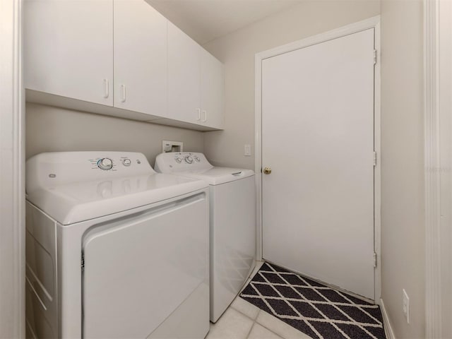 washroom with light tile patterned floors, washer and clothes dryer, and cabinets