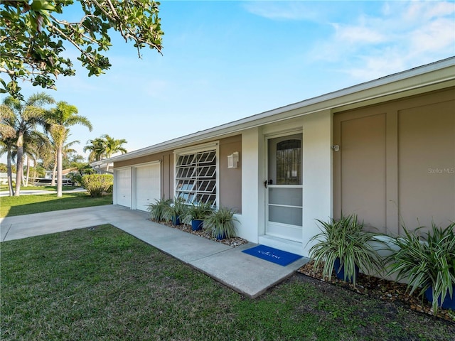 view of exterior entry featuring a garage and a lawn