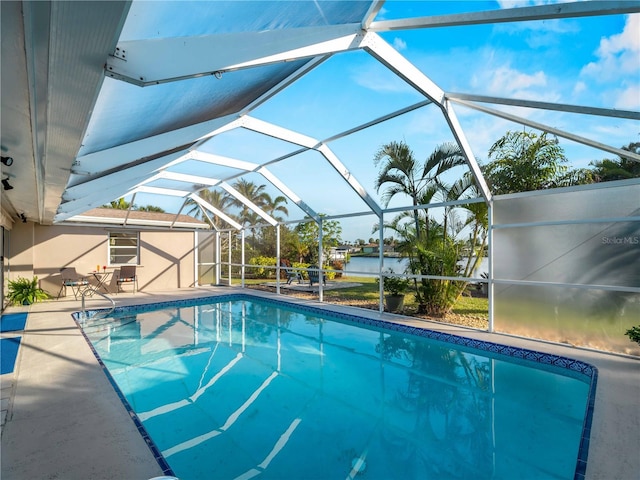 view of pool featuring a patio, a water view, and glass enclosure