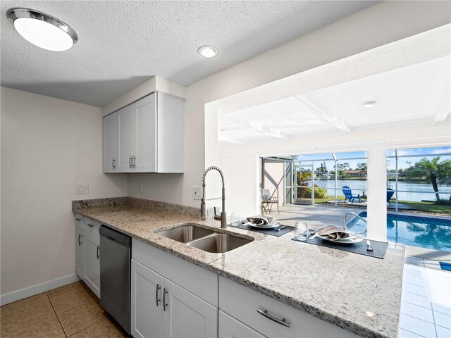 kitchen with sink, dishwasher, a water view, light stone countertops, and white cabinets