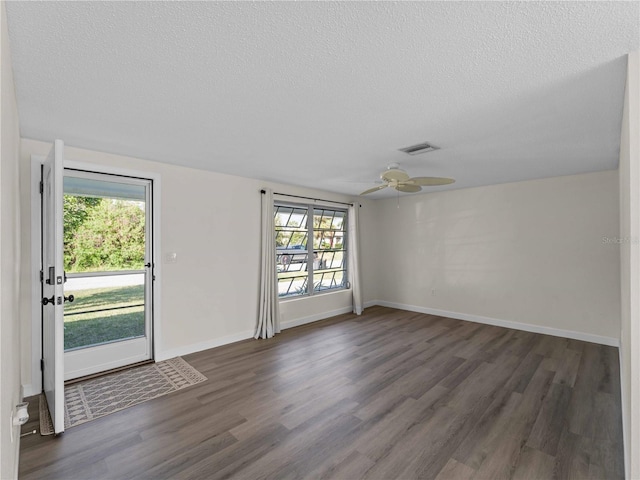 empty room featuring ceiling fan, dark wood-type flooring, and a textured ceiling