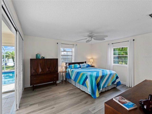 bedroom featuring a textured ceiling, multiple windows, and light wood-type flooring