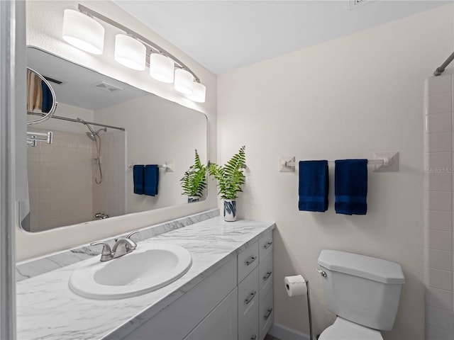 bathroom with a tile shower, vanity, and toilet