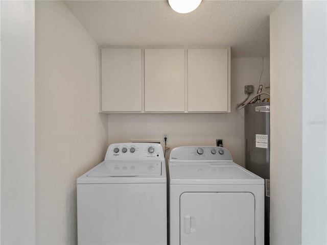 clothes washing area featuring cabinets, washing machine and dryer, a textured ceiling, and water heater