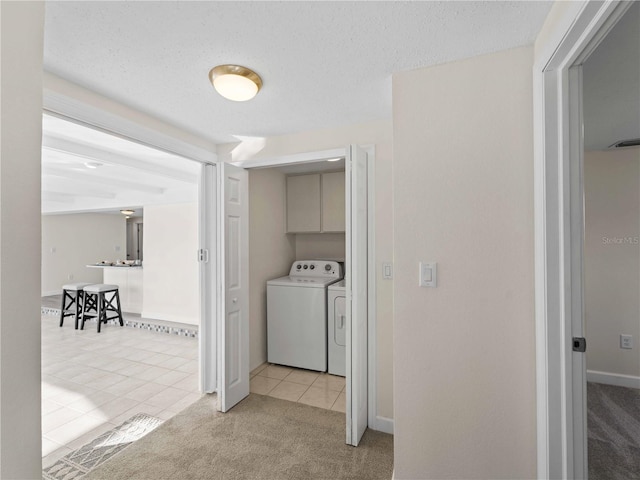 corridor with separate washer and dryer, light carpet, and a textured ceiling