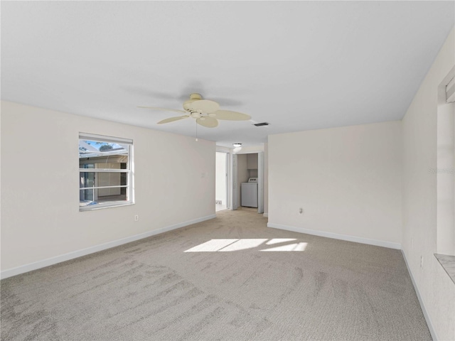 spare room featuring ceiling fan, light colored carpet, and washer / dryer