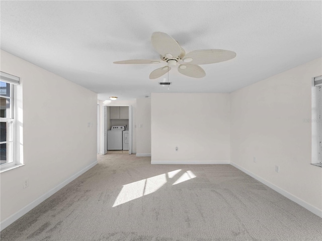 carpeted empty room featuring washing machine and clothes dryer and ceiling fan