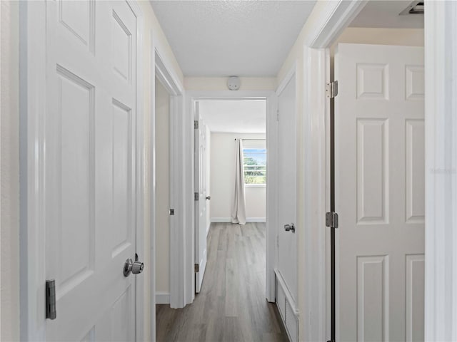 hallway featuring wood-type flooring and a textured ceiling