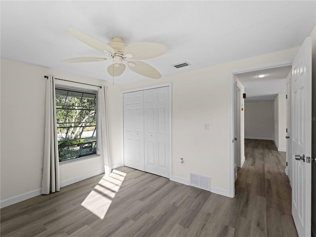 unfurnished bedroom featuring hardwood / wood-style flooring, ceiling fan, and a closet